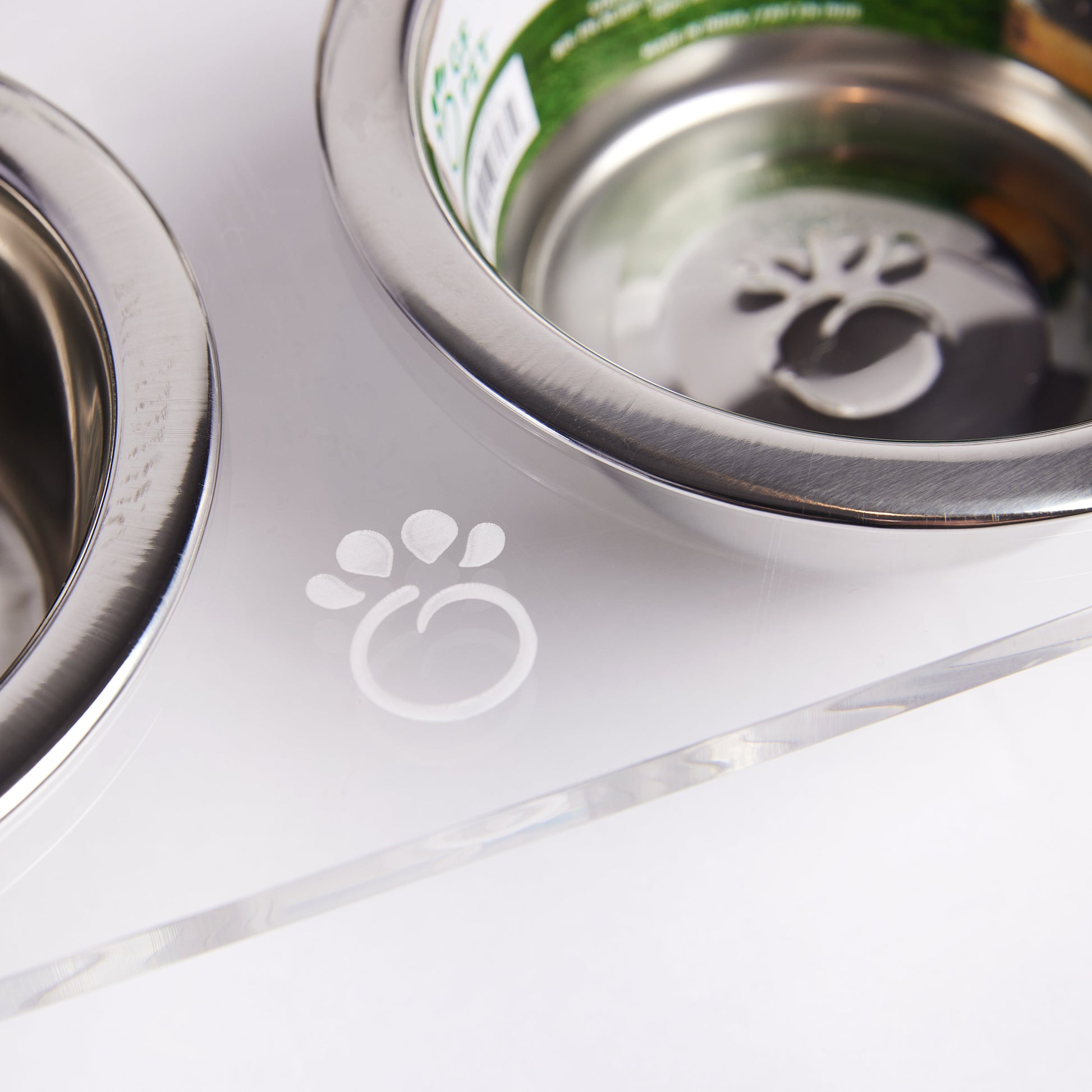 Close-up of stainless steel bowl on clear acrylic feeder with GF Pet paw logo engraved